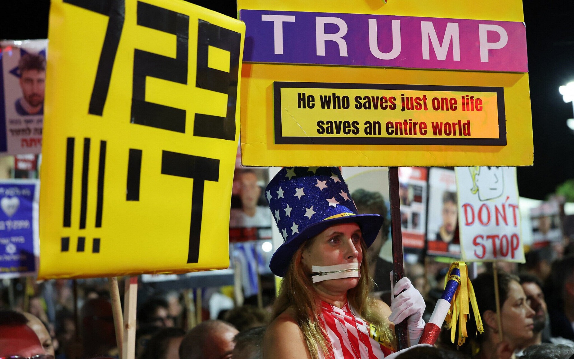 Una mujer con un vestido con los colores de la bandera estadounidense sostiene un cartel que insta al presidente de Estados Unidos, Donald Trump, a sellar un alto el fuego y un acuerdo sobre los rehenes en Gaza, durante una manifestación en apoyo de los rehenes en la Plaza de los Rehenes en Tel Aviv, Israel, el 4 de octubre de 2025. Foto: Jack Guez / AFP