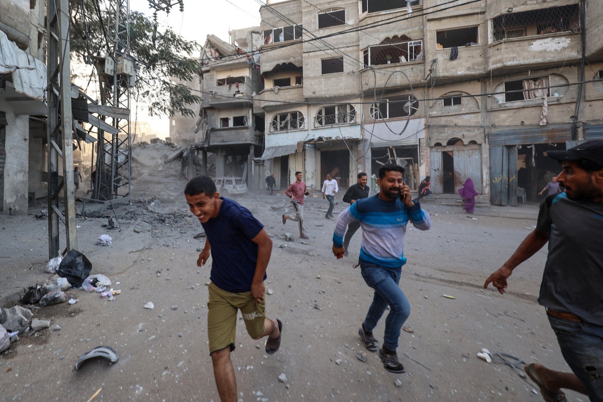 La gente corre a refugiarse tras un ataque israelí contra un edificio en el campamento de Bureij, en el centro de la Franja de Gaza, el 19 de octubre de 2025. Foto: Eyad Baba / AFP