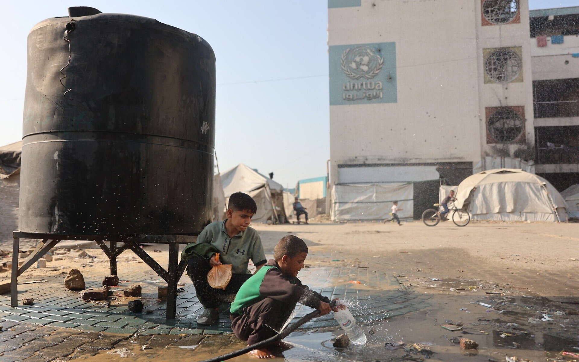 Un niño llena una botella de plástico con agua dentro de un campamento para palestinos desplazados, instalado en una escuela convertida en refugio en el barrio de Al-Rimal, en la ciudad de Gaza, el 5 de noviembre de 2025. La imagen refleja la dependencia de los desplazados de fuentes de agua limitadas y la importancia crítica de los servicios de abastecimiento en medio de la crisis humanitaria. Foto: Omar Al-Qattaa / AFP