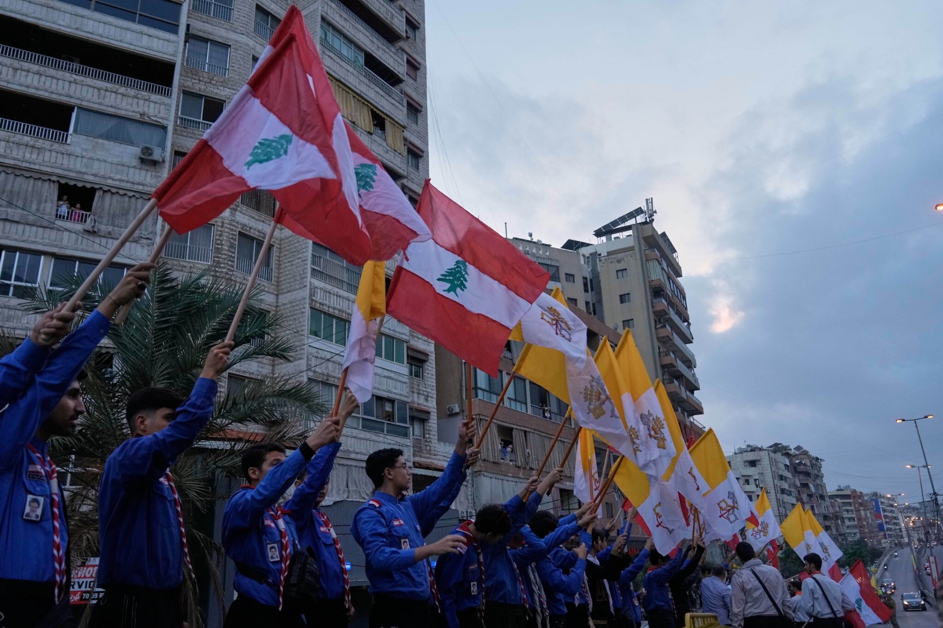 Scouts afiliados a Hezbolá ondean banderas libanesas y del Vaticano mientras esperan recibir al Papa León XIV a su llegada a Beirut, Líbano, el 30 de noviembre de 2025. La presencia de los scouts refleja la participación de distintos grupos sociales y políticos en la visita papal, así como la importancia del evento como un mensaje de coexistencia y unidad nacional, en un país marcado por divisiones sectarias y recientes conflictos con Israel. Foto: AP/Bilal Hussein