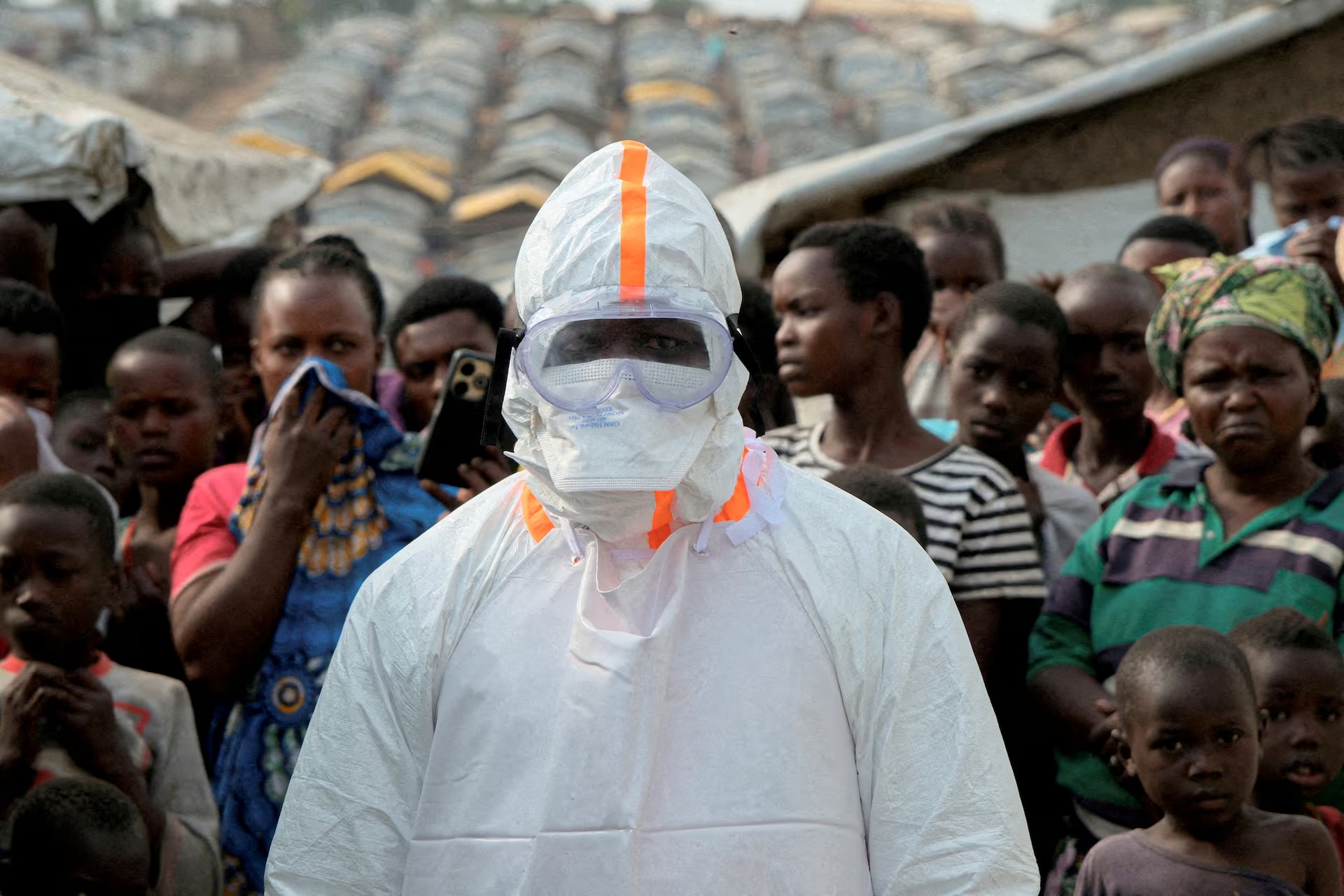 ARCHIVO. Un trabajador sanitario permanece junto a personas desplazadas que esperan el entierro de presuntas víctimas de ébola en el campamento de Kigonze, en Bunia, República Democrática del Congo, el 18 de junio de 2026. Foto: Reuters/Gradel Muyisa Mumbere