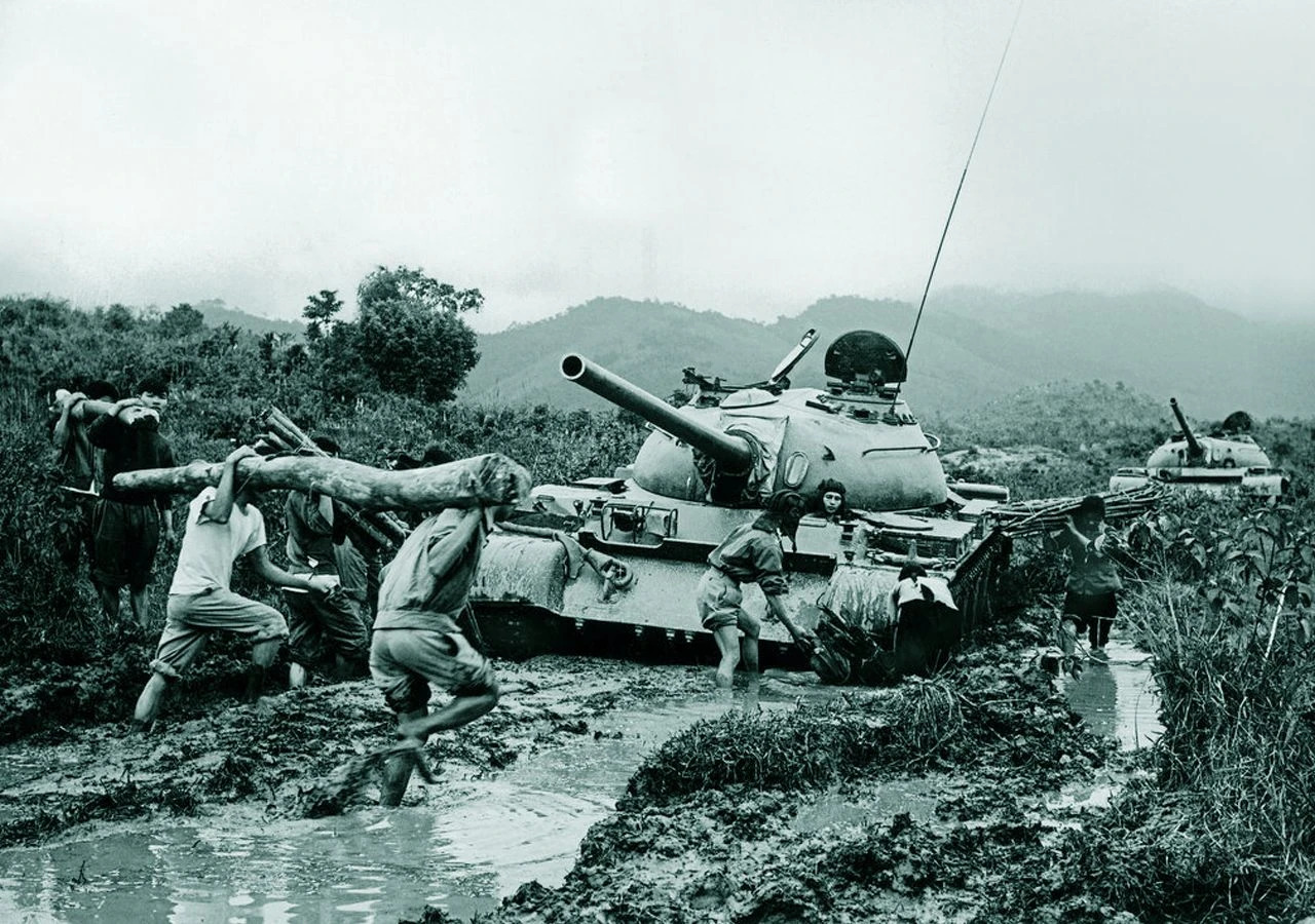 Soldados y milicianos norvietnamitas trabajan para liberar un tanque soviético T-54 atascado en un tramo embarrado de la Ruta Ho Chi Minh, en 1972. La fotografía, atribuida a Luong Nghia Dung, muestra las difíciles condiciones de una de las principales rutas logísticas utilizadas durante la Guerra de Vietnam. Fotografía: Luong Nghia Dung / Archivo Histórico