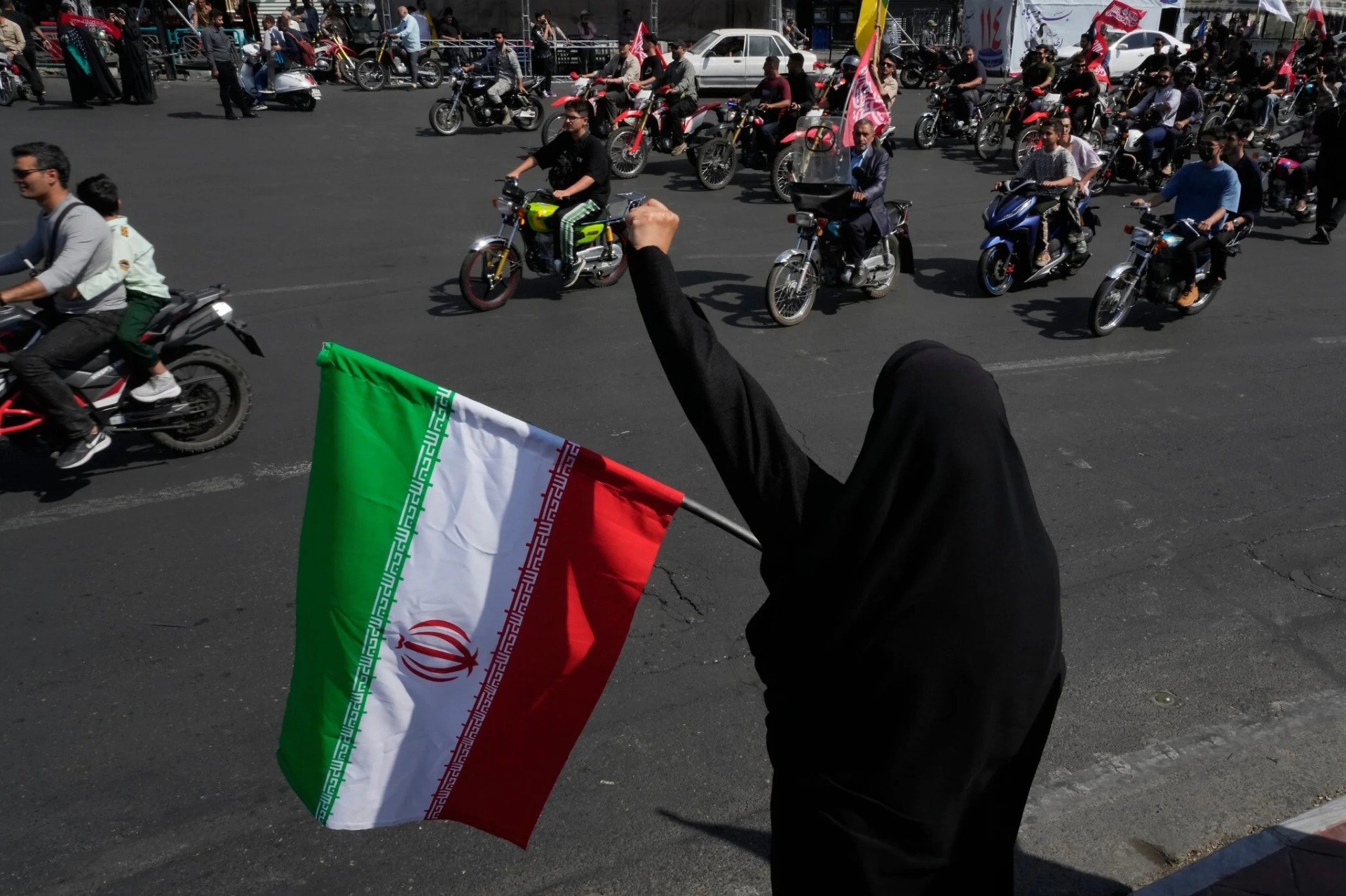 Una mujer corea consignas mientras sostiene una bandera iraní durante un desfile estatal de motocicletas denominado “Janfada”, que significa “Sacrificio por Irán”, en Teherán, Irán, el 25 de septiembre de 2026. La movilización se produjo mientras el país continúa bajo una fuerte presión económica y en medio de las negociaciones con Estados Unidos para intentar poner fin a la guerra. Foto: AP / Vahid Salemi